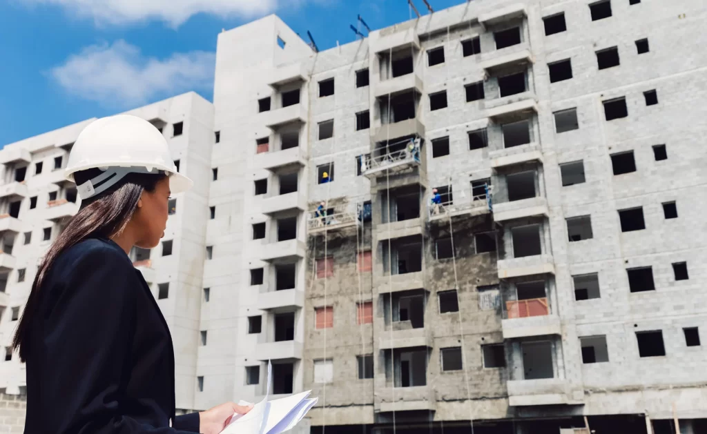 Ingeniera con papeles cerca del edificio en construcción.