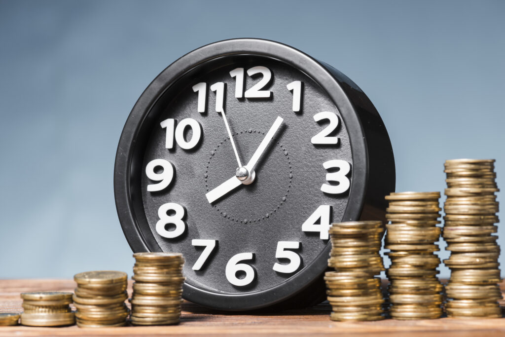 Reloj rodeado de monedas, sobre las horas extras en México con la reforma laboral
